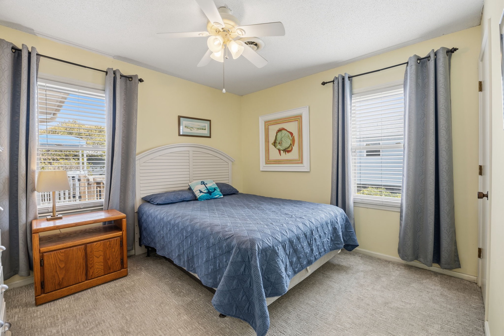 Rest peacefully in your comfortable bedroom with soft linens, gentle ceiling fan breeze, and natural light streaming through dual windows.