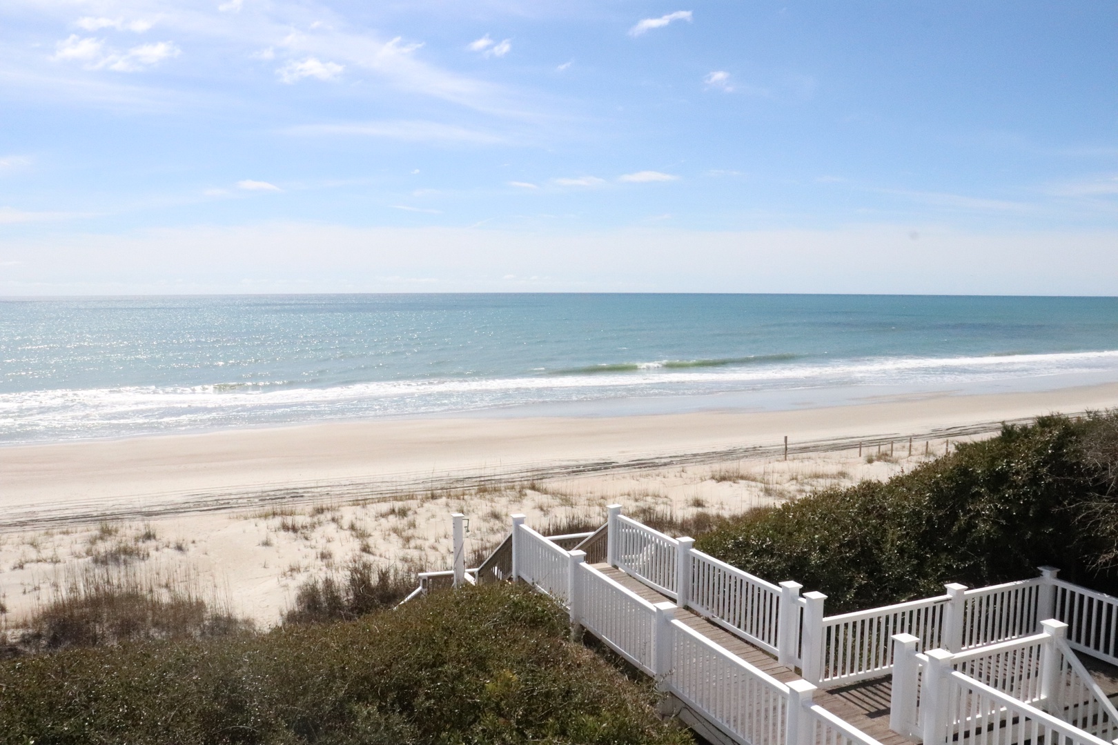 Pristine oceanfront with private walkway leading to expansive sandy beach and rolling waves.