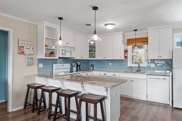 Your fully equipped kitchen awaits with granite counters, white cabinets, and a breakfast bar where you can enjoy morning coffee together.