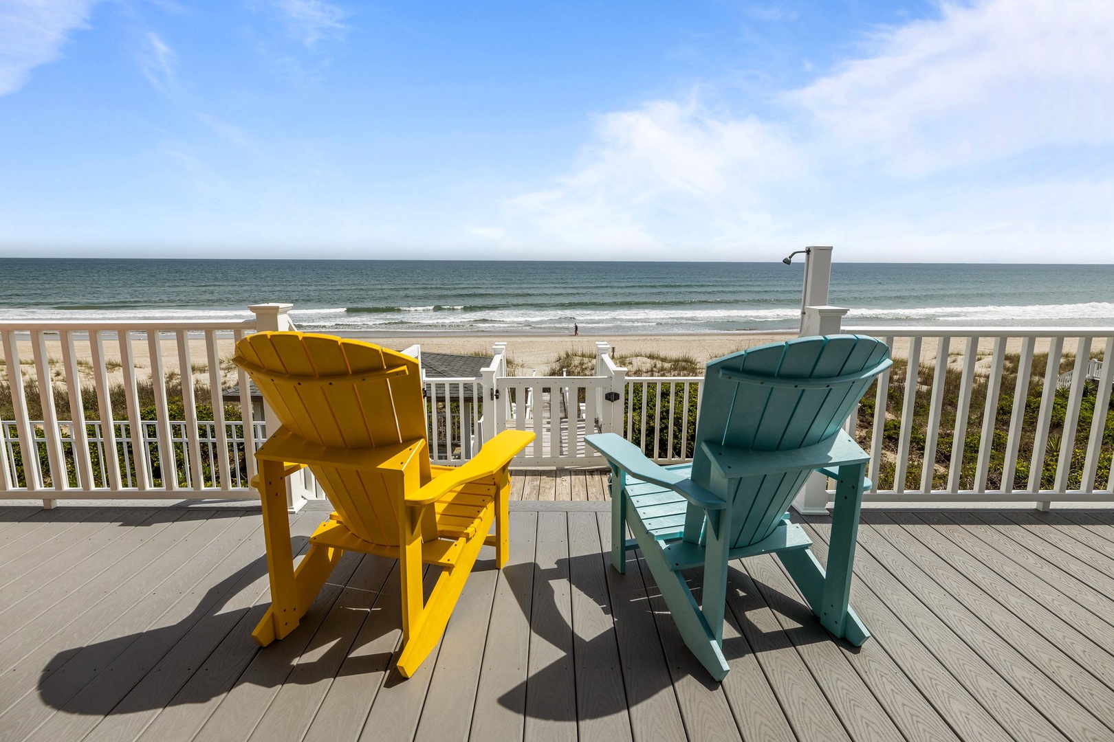 Unwind in colorful Adirondack chairs on your private deck, where ocean waves and endless beach views create the perfect coastal escape.