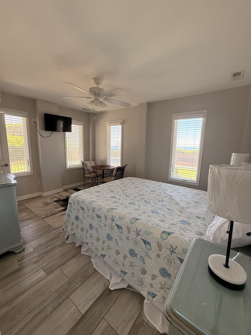 Your peaceful retreat features a plush bed with coastal-inspired linens, bright natural light streaming through multiple windows, and tasteful furnishings designed for your comfort and relaxation.