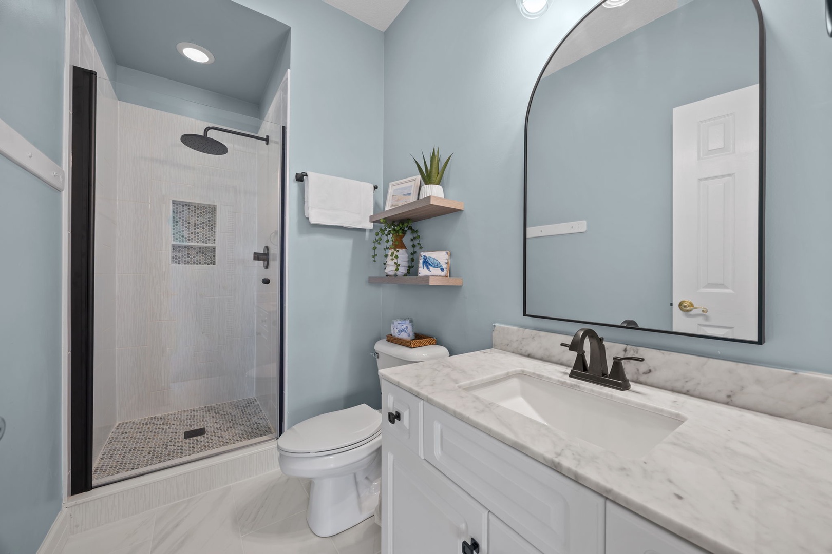 Refresh yourself in this spa-like bathroom with its calming blue walls, marble countertops, and elegant walk-in shower with rainfall showerhead.
