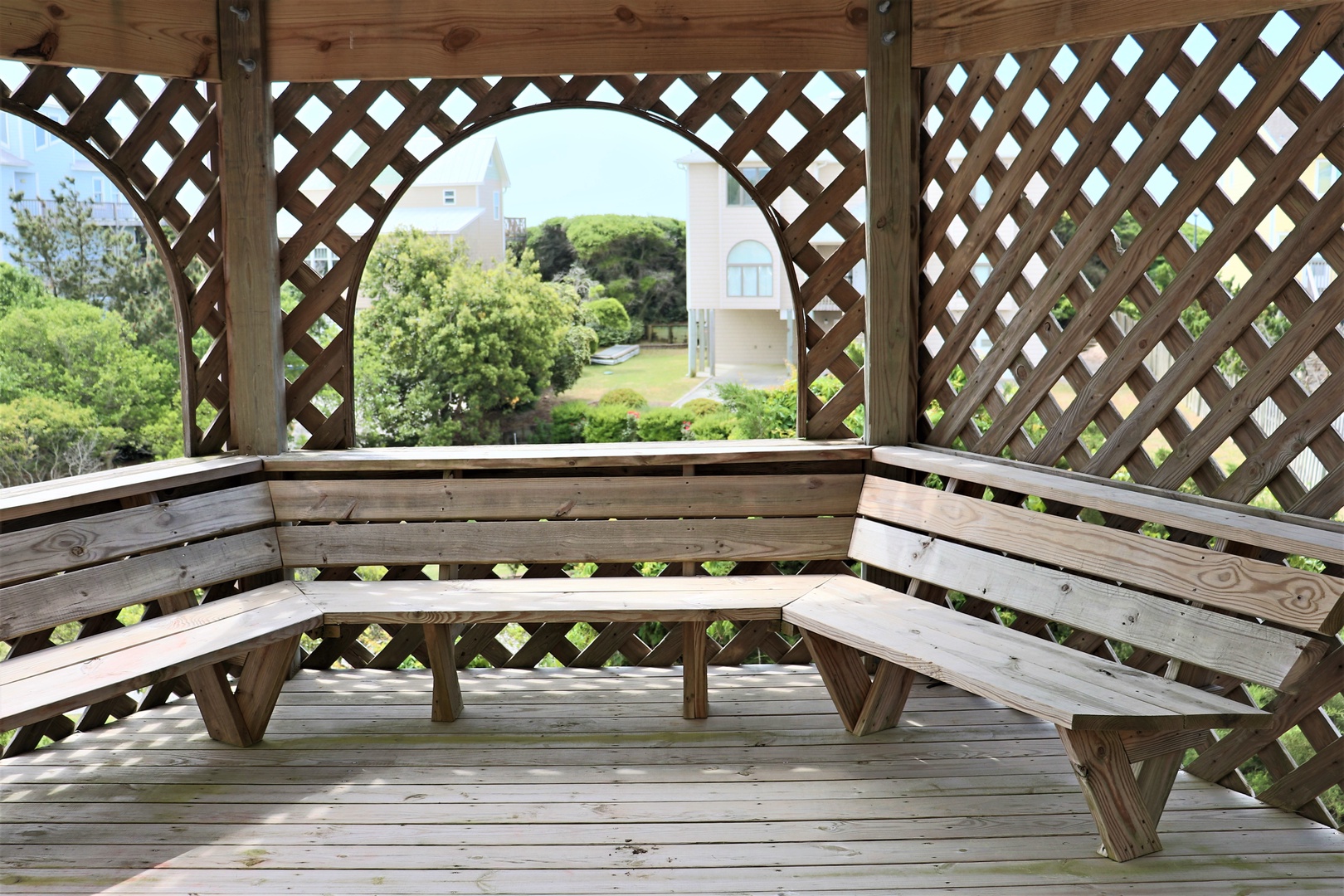 Escape to your private wooden gazebo where curved benches invite peaceful moments overlooking lush gardens and charming architecture.