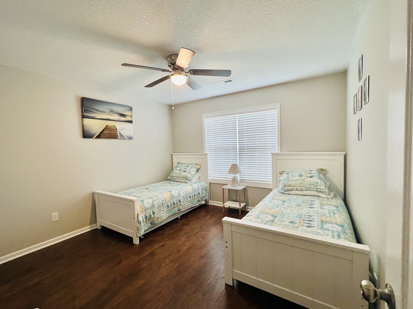 Your comfortable twin bedroom offers peaceful sleep with soft coastal bedding and gentle ceiling fan breeze.