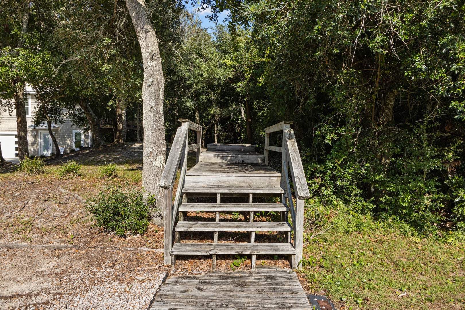A charming wooden bridge leads through lush trees, connecting paths around the peaceful property grounds.