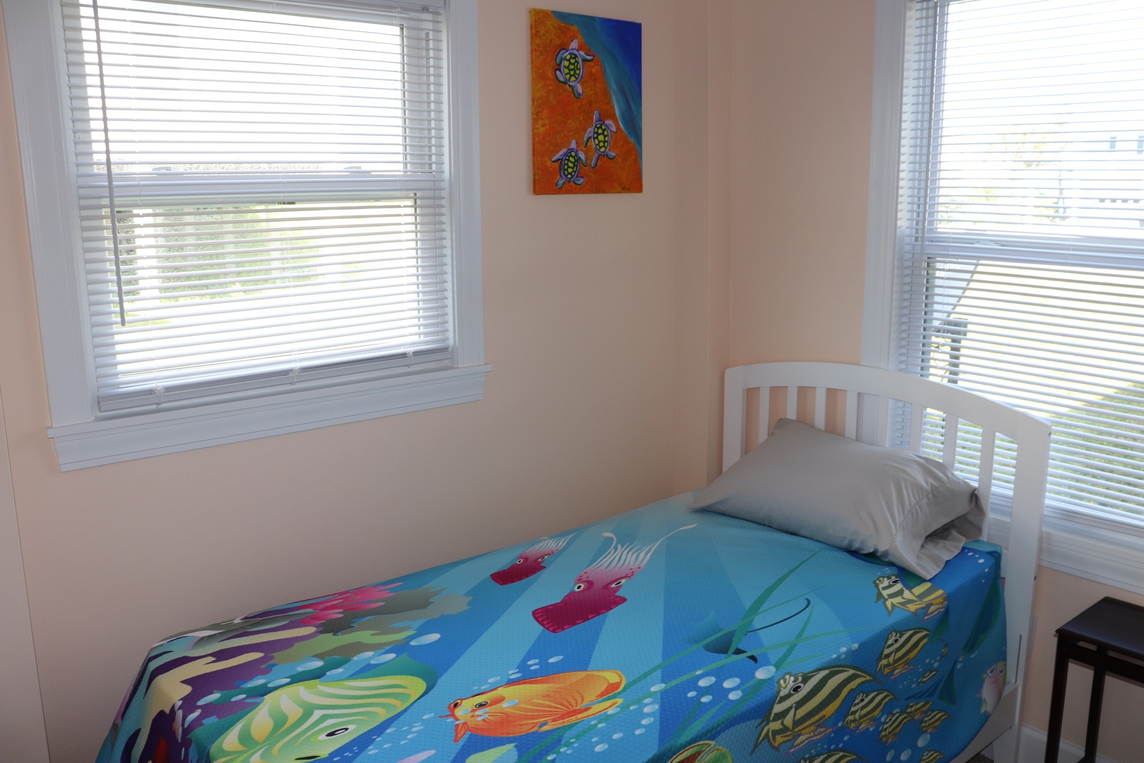 Drift off to sleep in your bright corner bedroom, where colorful sea-themed bedding and cheerful artwork create a playful coastal retreat.