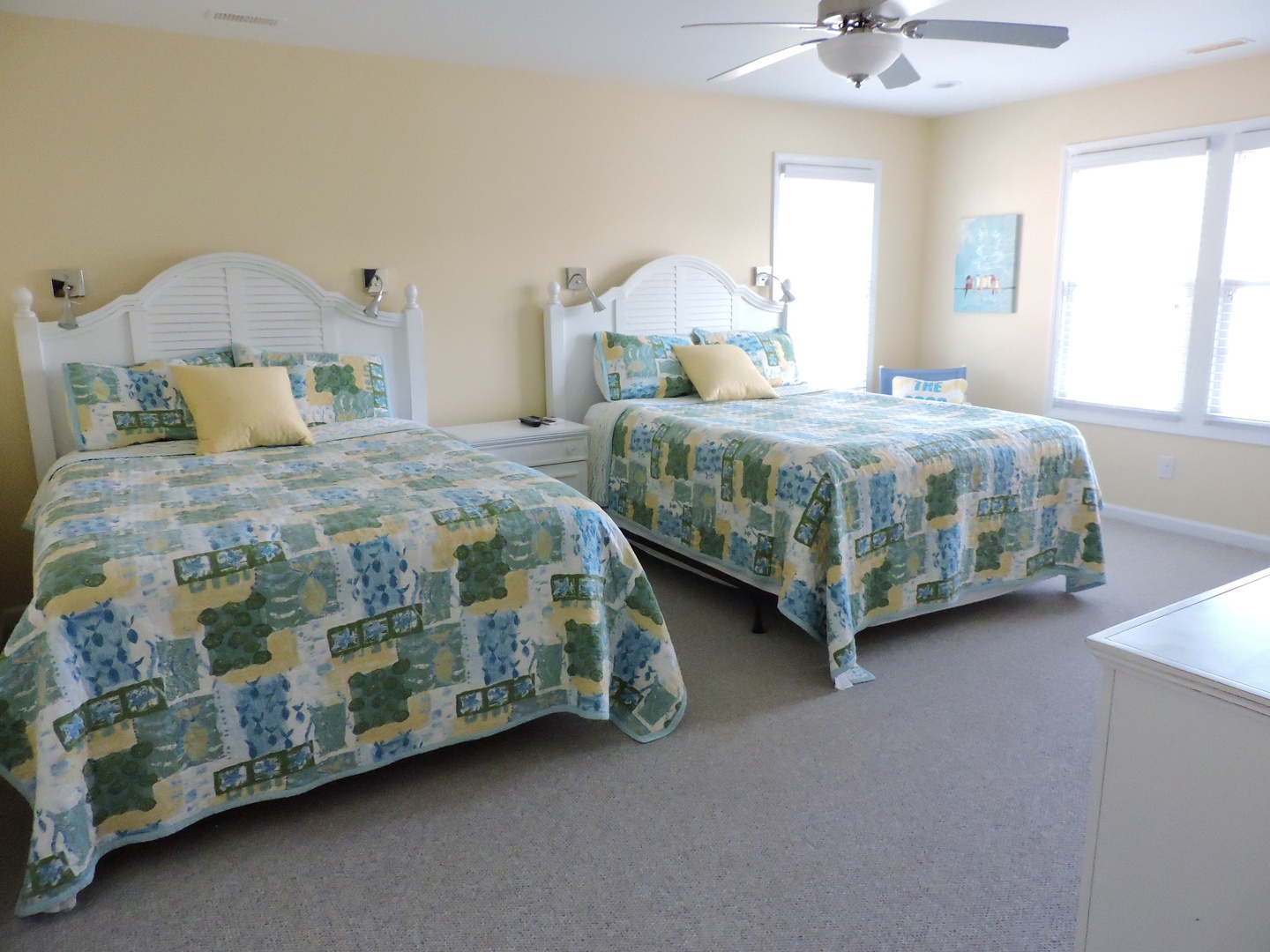 Rest peacefully in this bright twin bedroom with coastal-themed linens and gentle ceiling fan breeze.