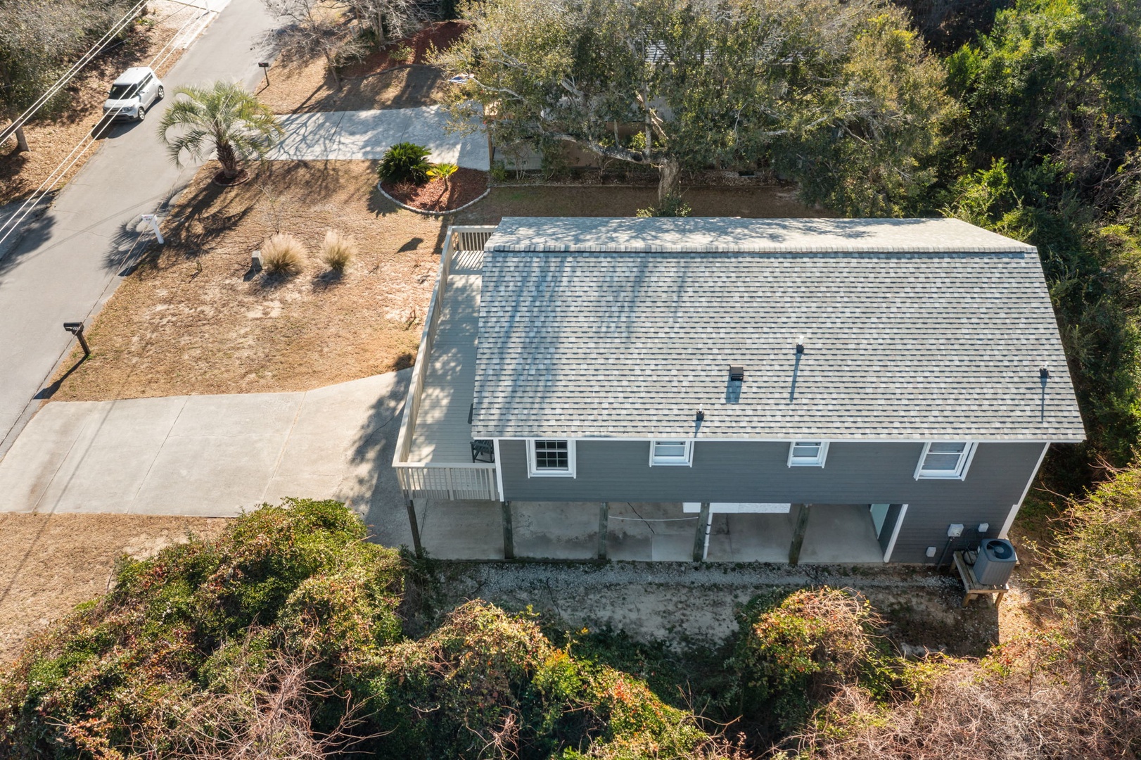 Aerial view of the property showing the main building with parking area and natural landscaping surrounding the home.