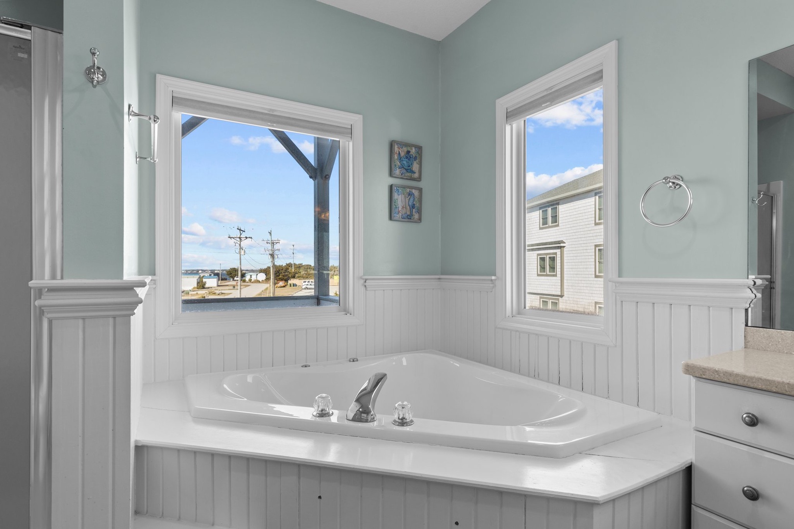 Soak in your coastal tub with serene water views through bright windows. Calming mint walls create perfect relaxation.