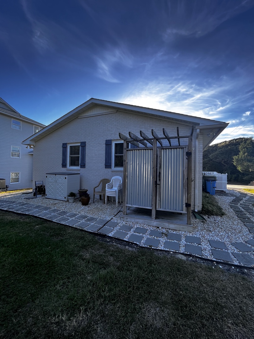 A charming countryside property featuring classic architecture with multiple buildings set against rolling green fields and expansive blue skies.