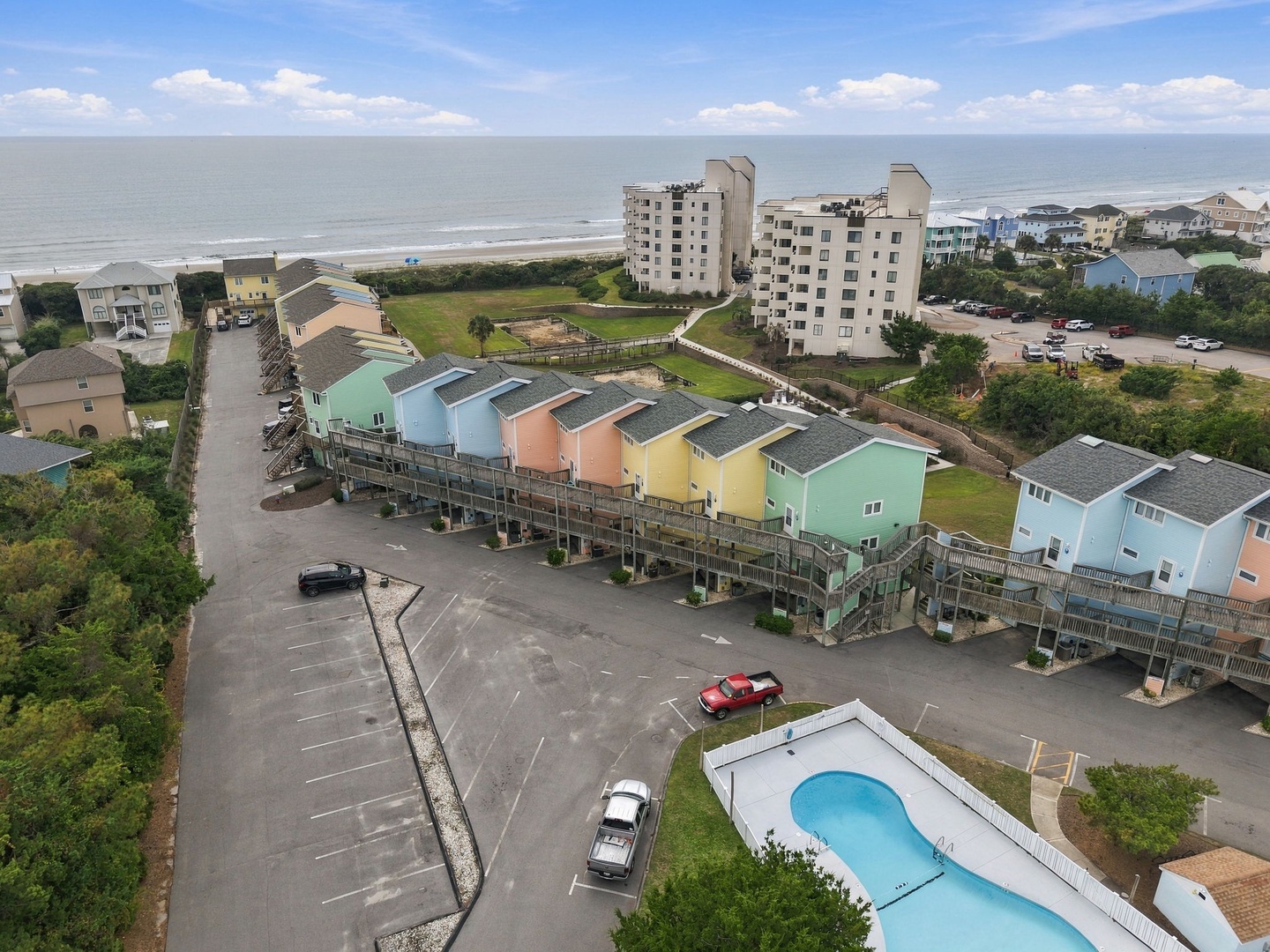 Beachfront vacation community featuring colorful rental cottages, shared pool, and convenient parking just steps from the sandy shore and ocean.