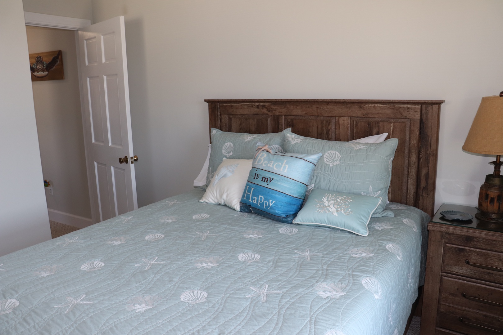 Drift into peaceful sleep in your cozy bedroom featuring coastal-themed linens and warm wooden furnishings that create the perfect seaside retreat atmosphere.