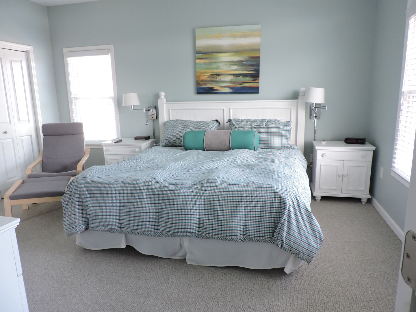 Sink into your peaceful coastal bedroom retreat with soothing aqua walls, crisp white furnishings, and a cozy reading chair by the window.