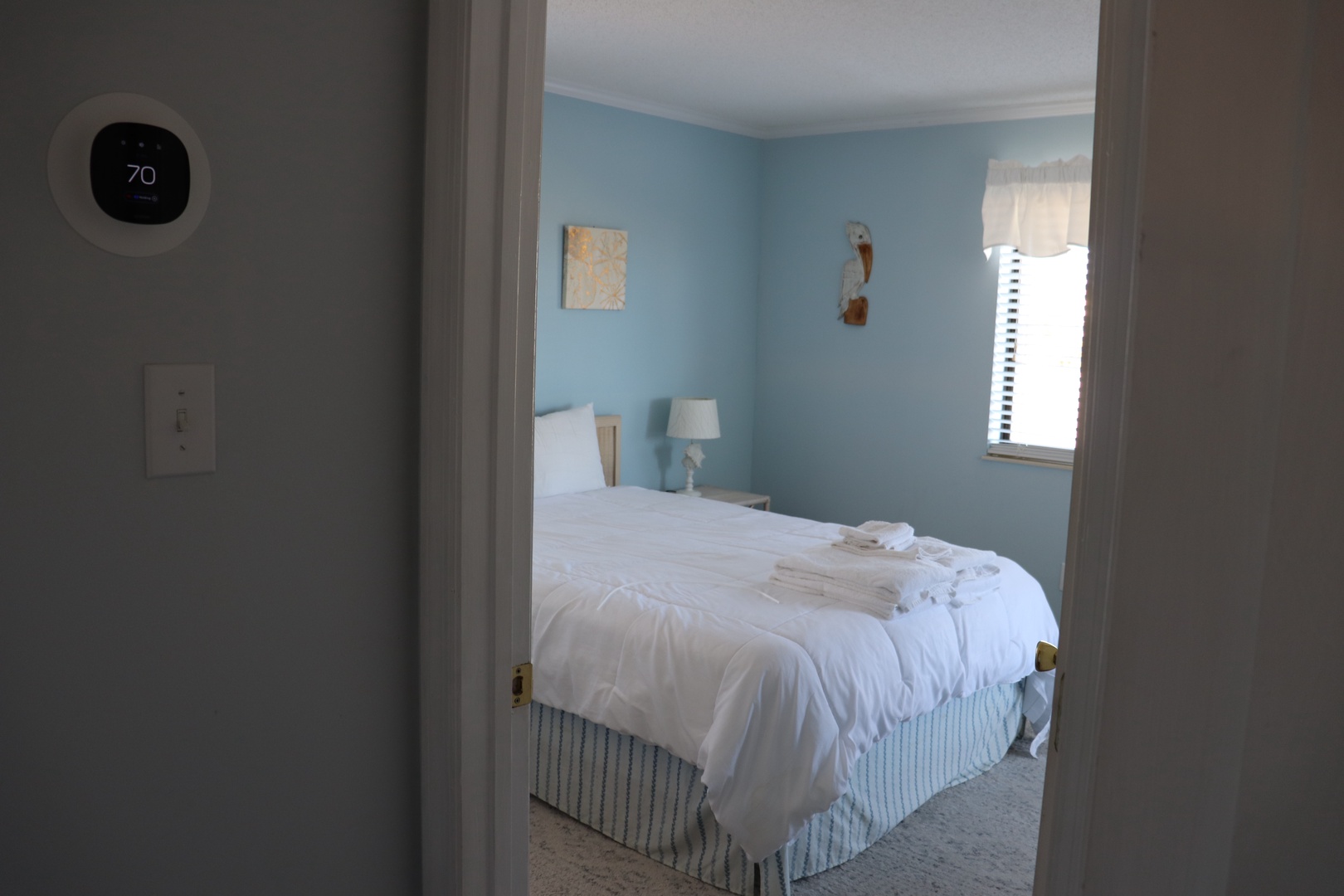 Your comfortable bedroom awaits with crisp linens, soothing blue walls, and perfect climate control for restful nights.