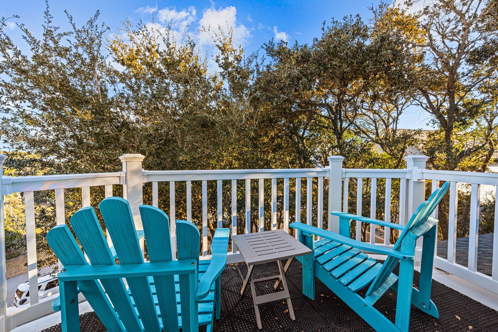 Your private deck awaits with turquoise chairs overlooking autumn trees—perfect for morning coffee or evening relaxation in this peaceful treetop setting.