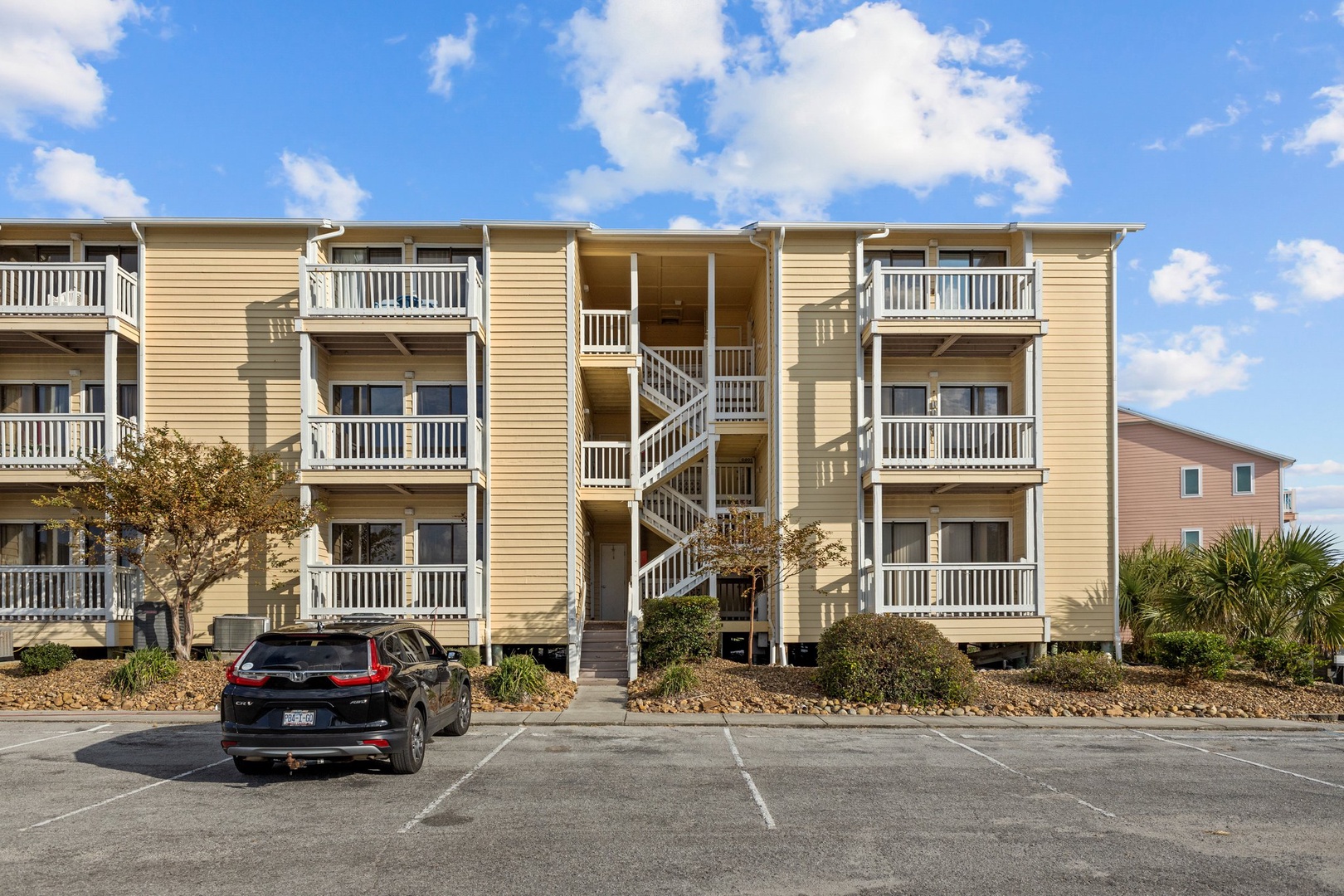 Coastal property building featuring multiple levels with private balconies and convenient parking spaces for guest arrival.