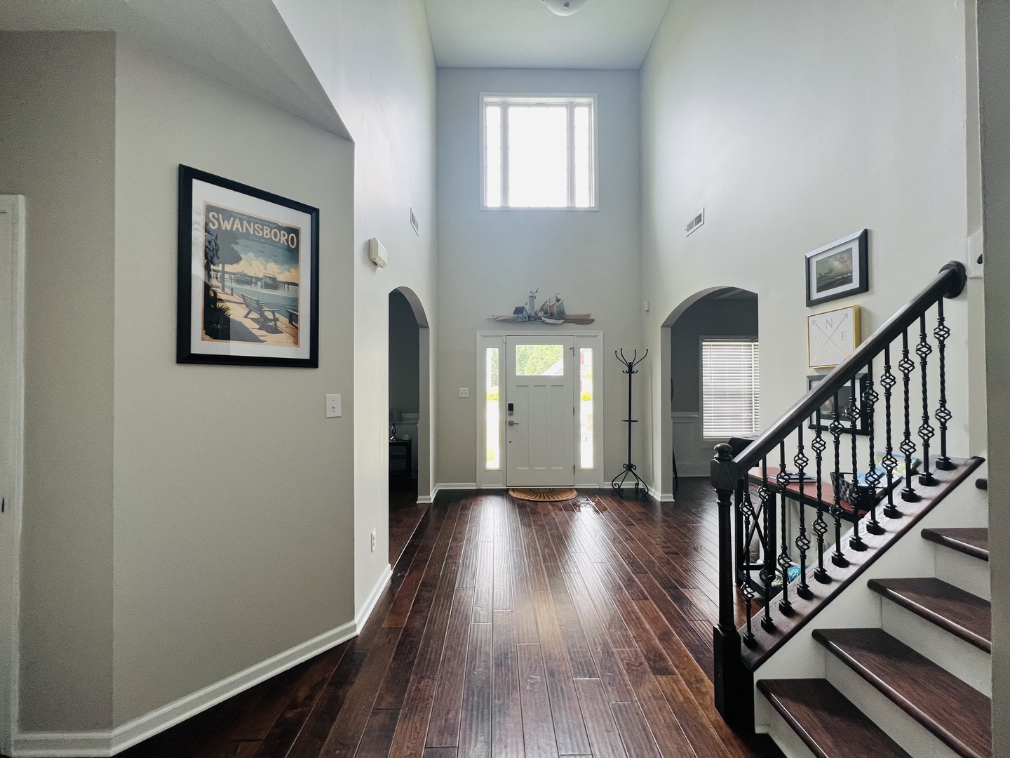 Step into your grand foyer where soaring ceilings and rich hardwood floors create an impressive welcome. Natural light floods through windows above.
