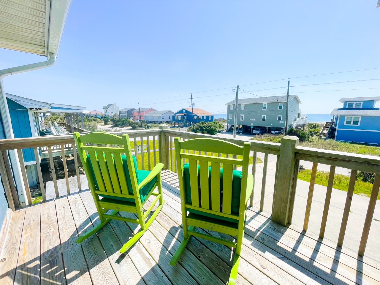 Relax on your private deck with colorful chairs while soaking in the charming coastal neighborhood views.
