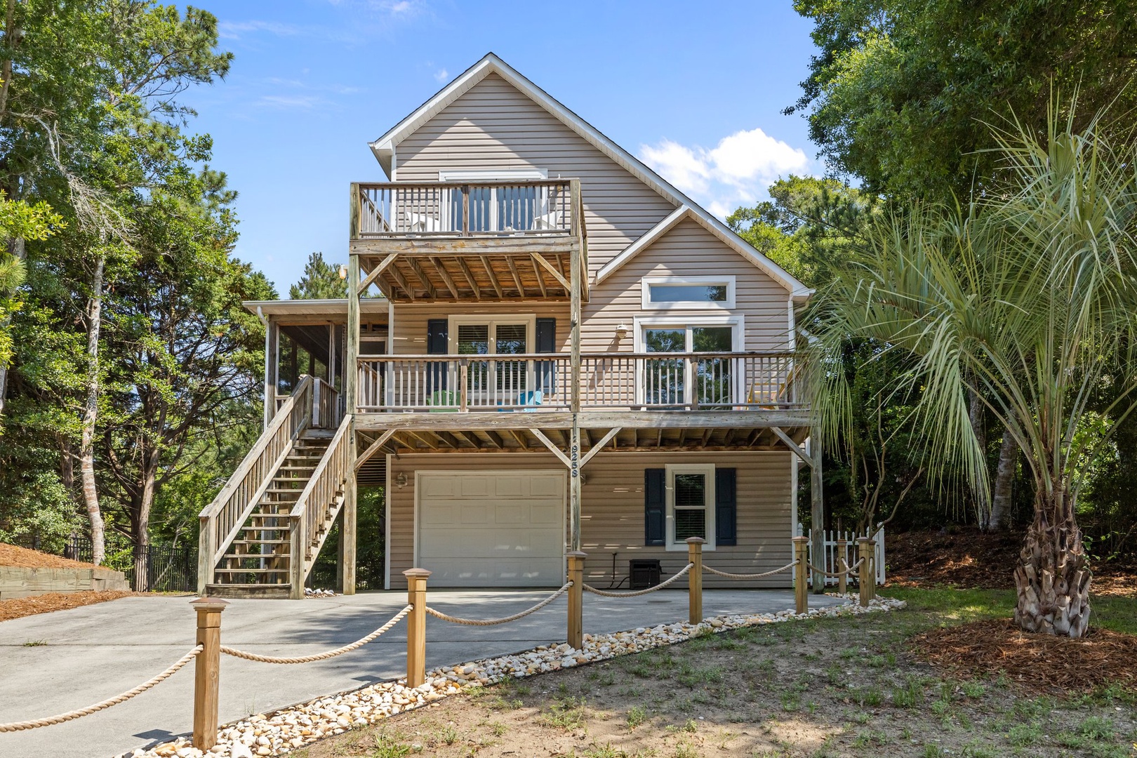 This beautifully designed coastal home features multiple decks and tropical landscaping in a peaceful wooded setting.