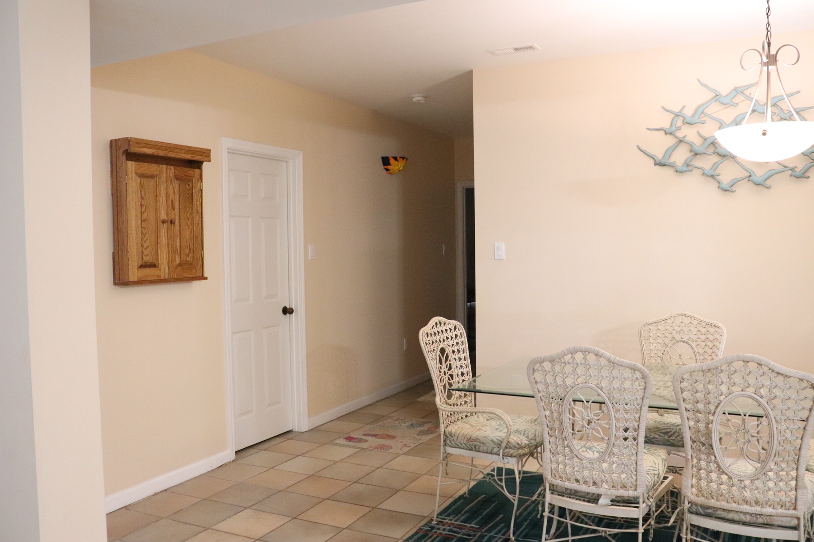 Gather around the elegant glass dining table with coastal-inspired wicker chairs for memorable meals together.