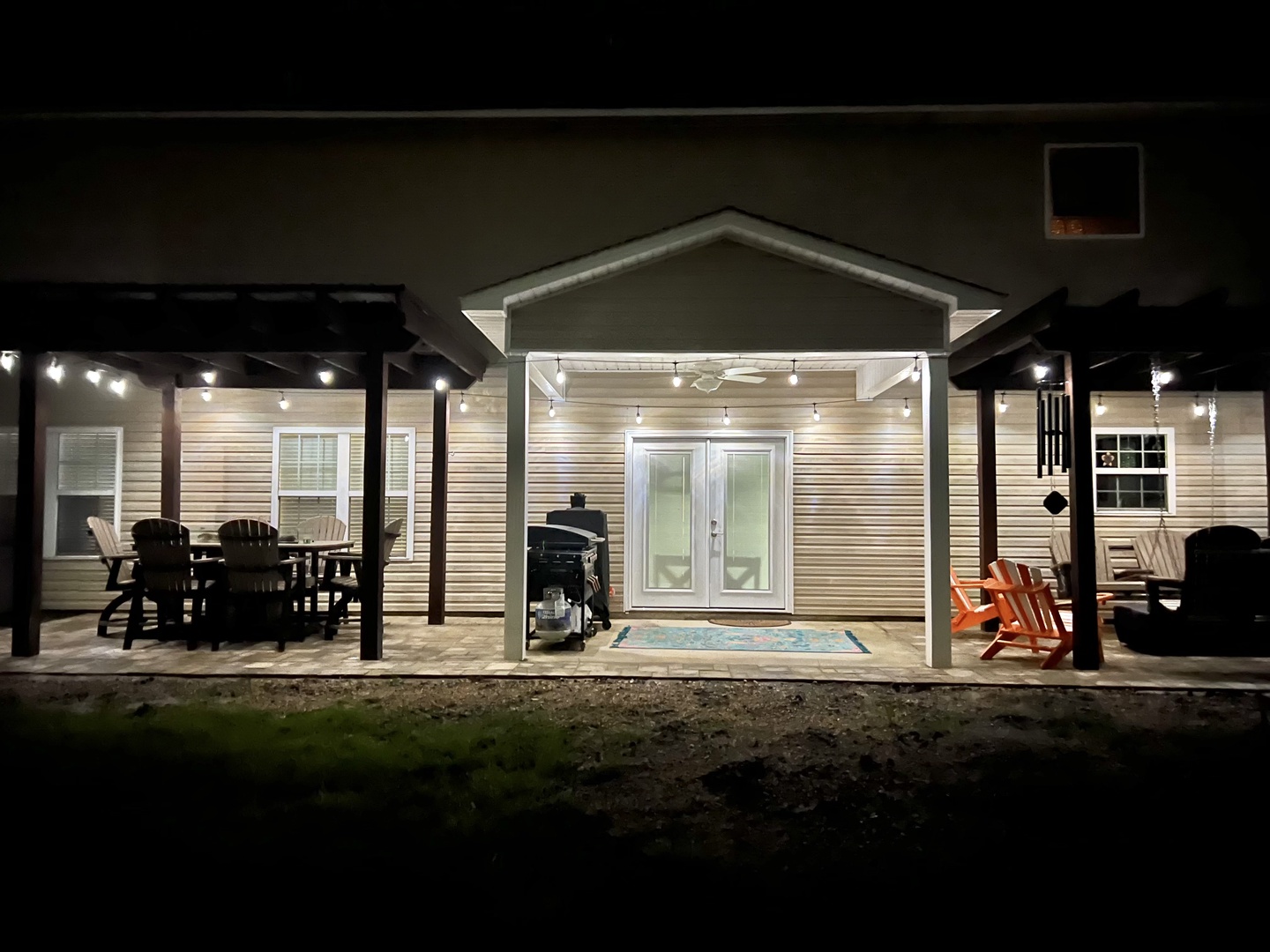 Evening exterior view showcasing the property's welcoming facade with outdoor seating areas and atmospheric string lighting.