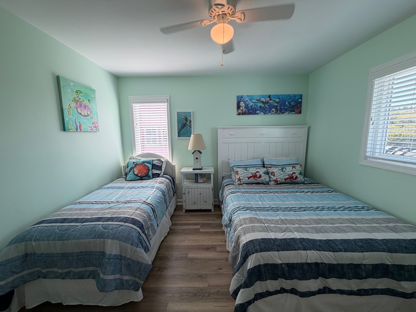 Wake up in your ocean-themed twin bedroom with sea turtle art and gentle ceiling fan breezes creating the perfect coastal retreat atmosphere.