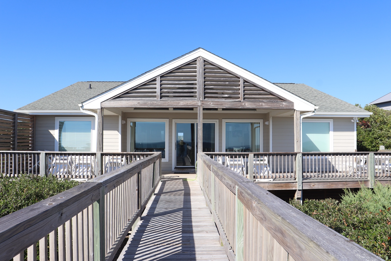 Beachfront cottage with wraparound deck and boardwalk entrance provides coastal charm.