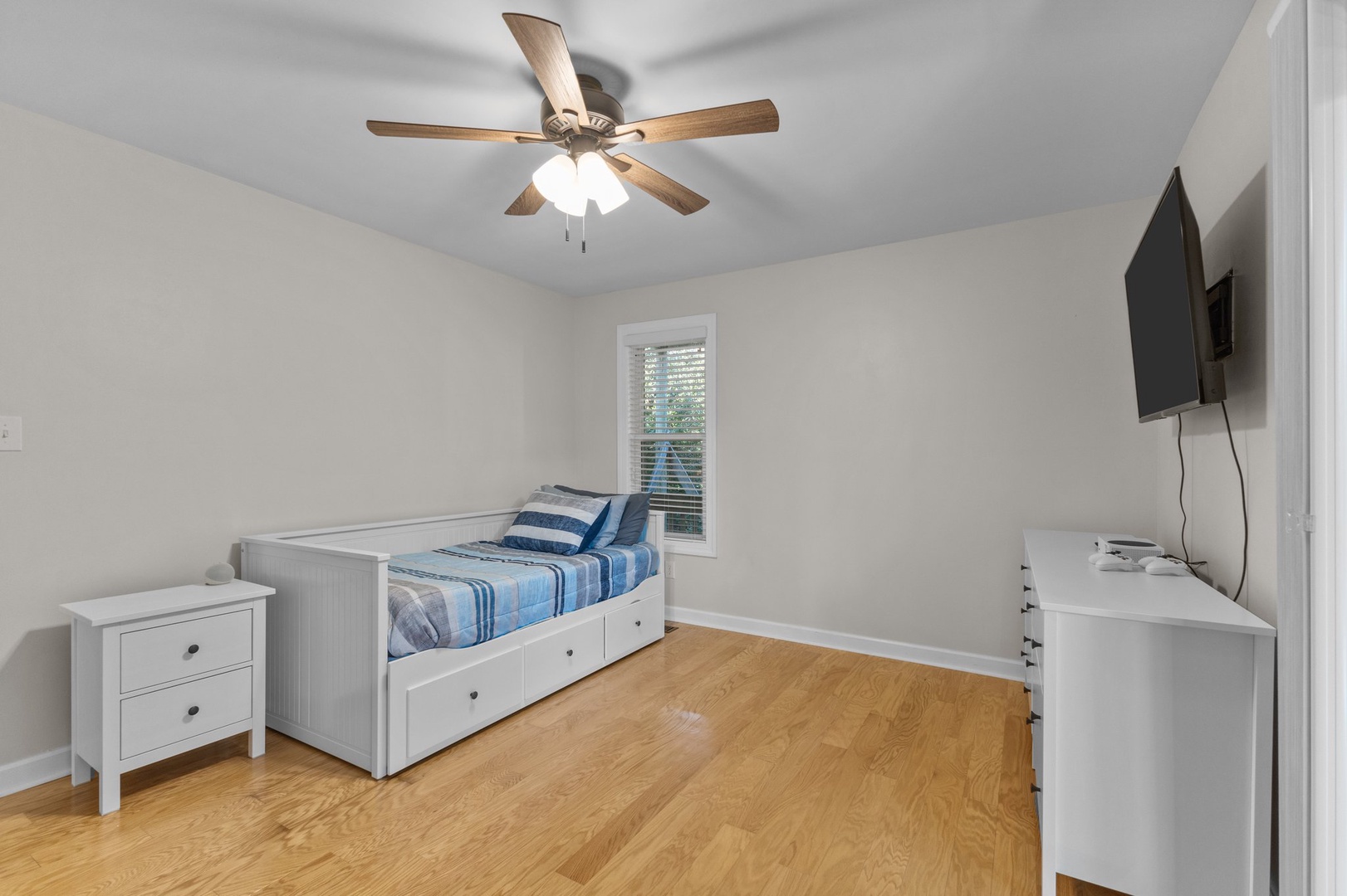 Unwind in your bright, cozy bedroom with warm wood floors, ceiling fan for comfort, and TV for relaxing evenings.