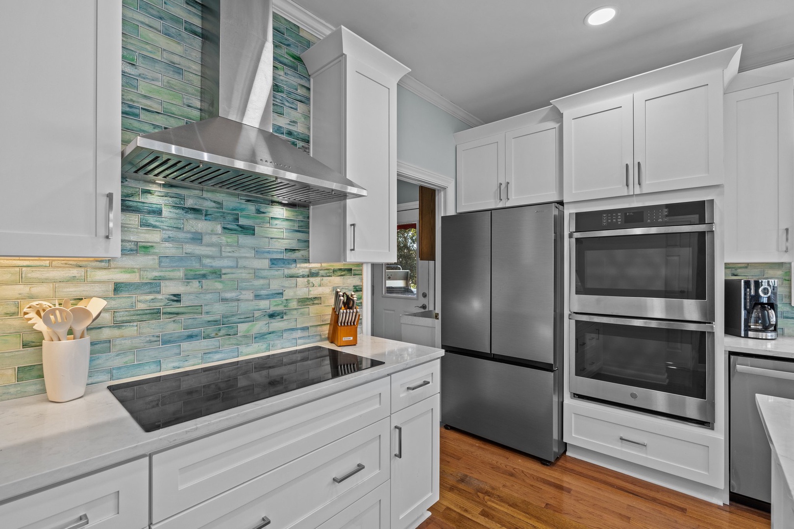 Cook your favorite meals in this stunning modern kitchen featuring premium stainless steel appliances and gorgeous sea-glass backsplash tiles.