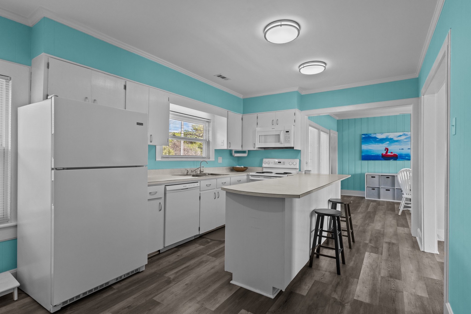 Step into your bright, coastal-themed kitchen with fresh turquoise walls, full appliances, and a breakfast bar for morning coffee.
