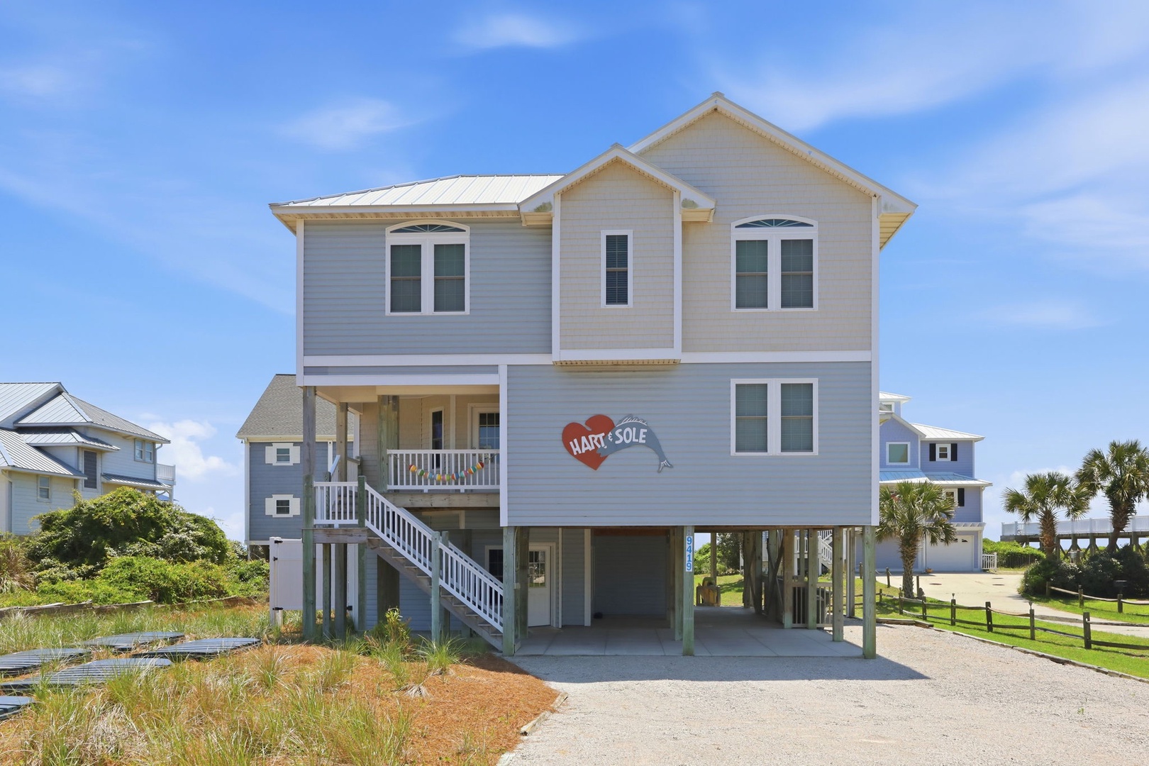 Coastal beach house with elevated construction and covered parking area, located in a beachfront neighborhood with ocean access.