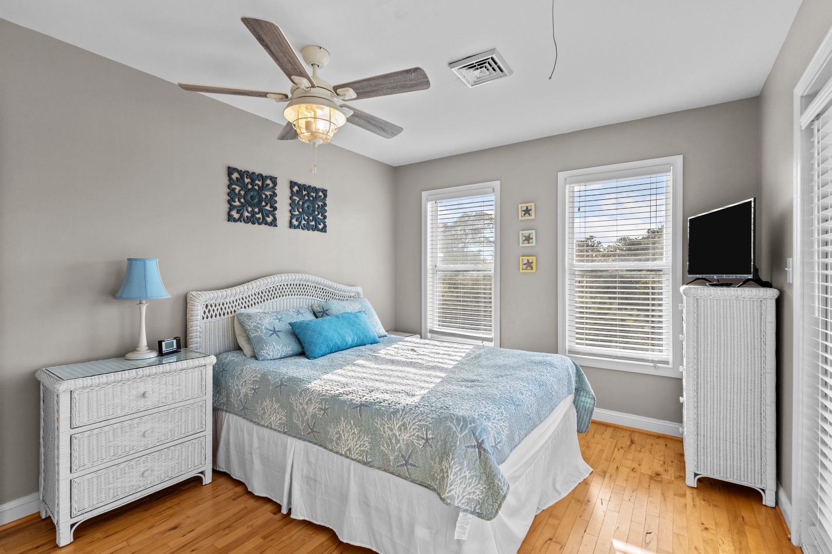 Drift off in your coastal-themed bedroom with soft blues, natural textures, and warm hardwood floors beneath your feet.