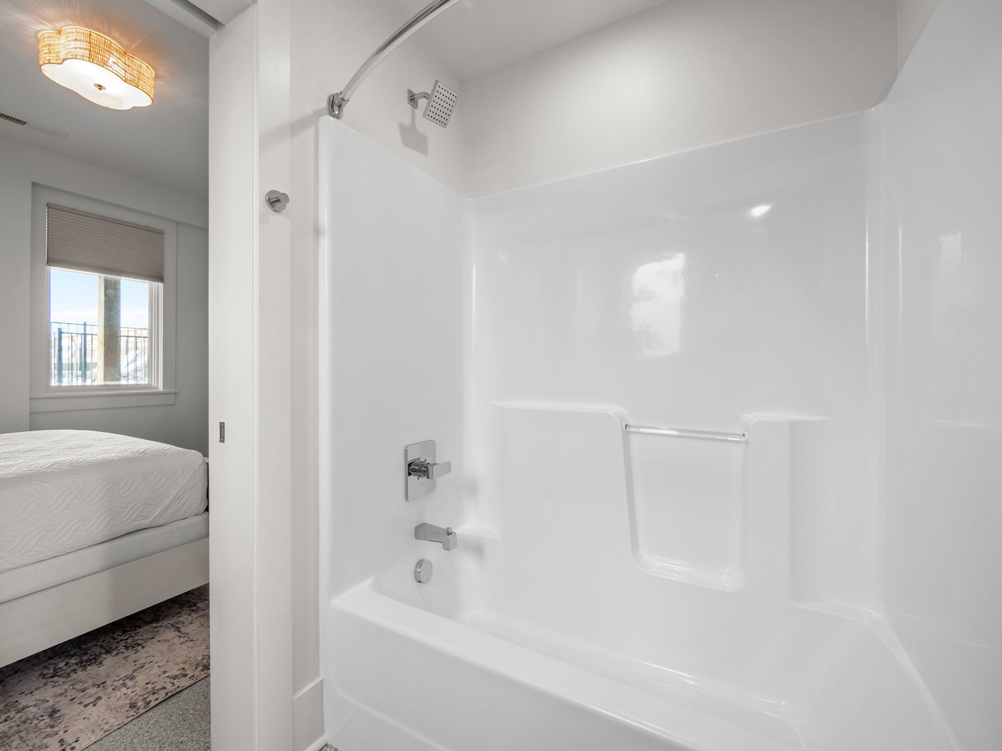 Step into your pristine white bathroom with sleek tub-shower combo and elegant lighting creating a spa-like retreat.