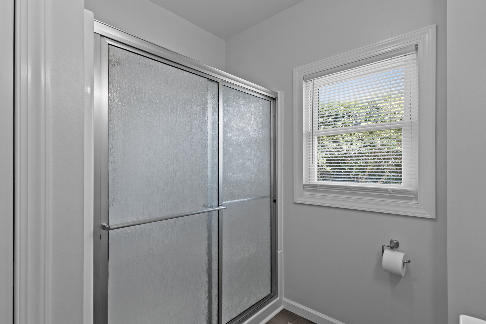 Step into your private spa-like retreat with a spacious glass shower and natural light streaming through frosted windows.