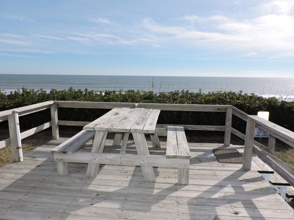 Oceanfront deck with picnic table overlooking pristine beach and endless sea views.