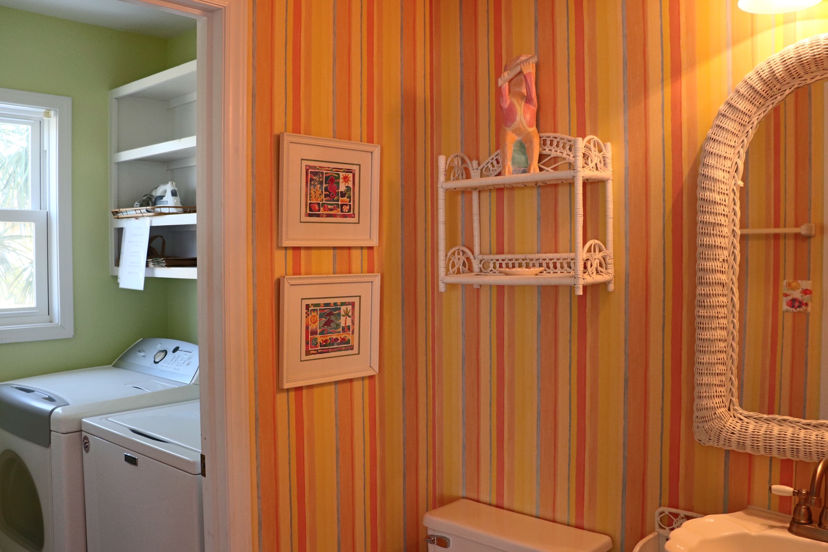 Step into your bright, cheerful bathroom with vibrant striped walls, decorative shelving, and a spacious wicker chair for your comfort.