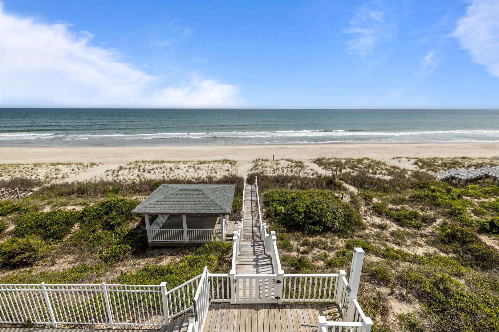 Beachfront property featuring direct ocean access via private boardwalk through protected dunes to pristine sandy shore.