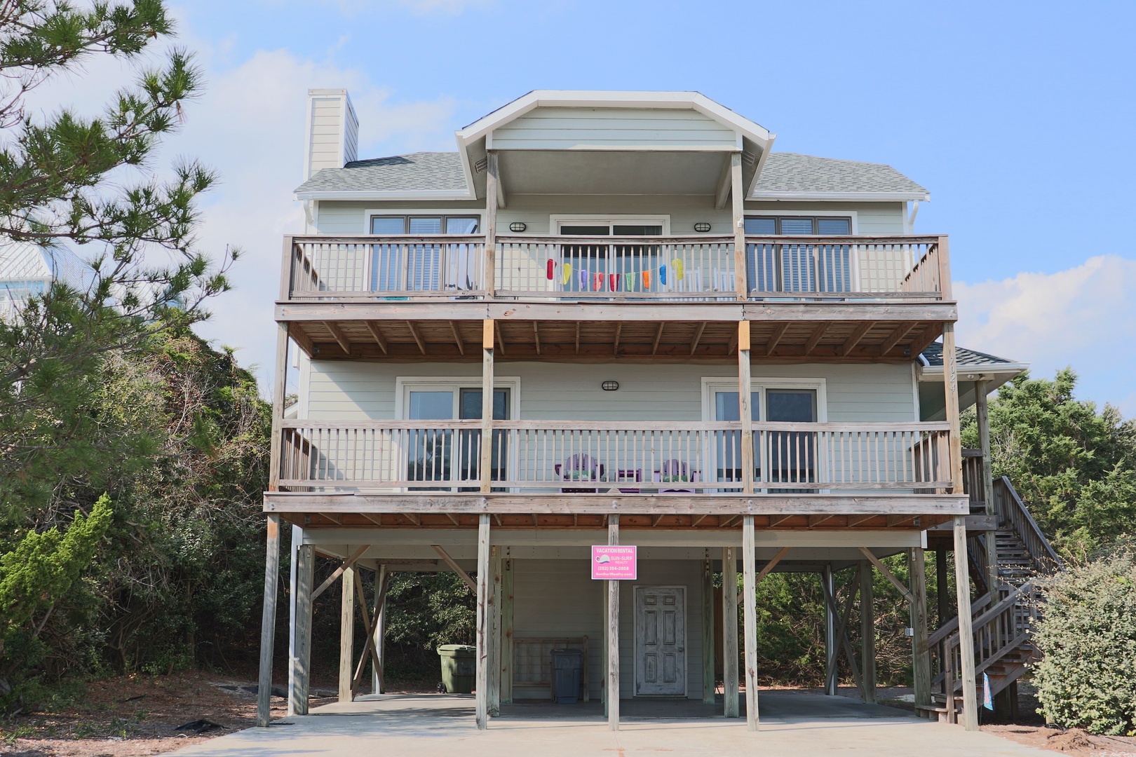 Multi-level beach house with spacious balconies and elevated design surrounded by coastal vegetation.