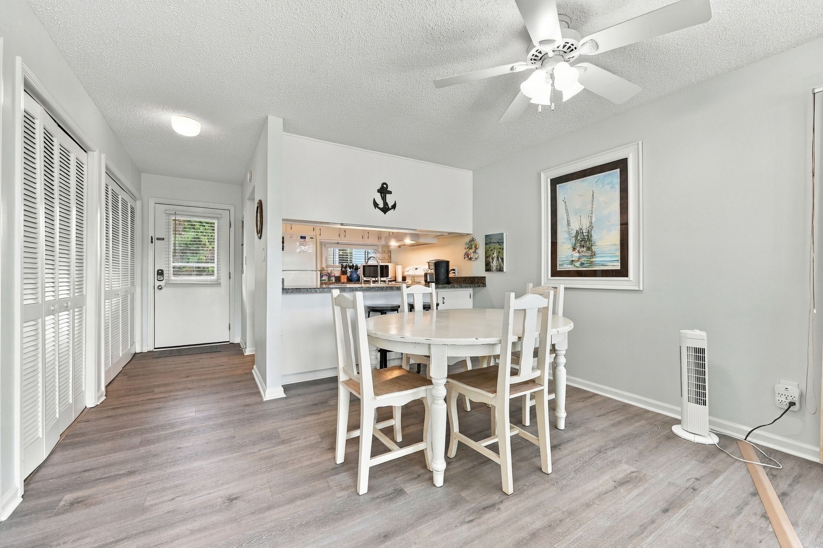 Settle into your bright, open dining space with coastal charm, where a welcoming table awaits your morning coffee or evening meal beneath the gentle breeze of the ceiling fan.