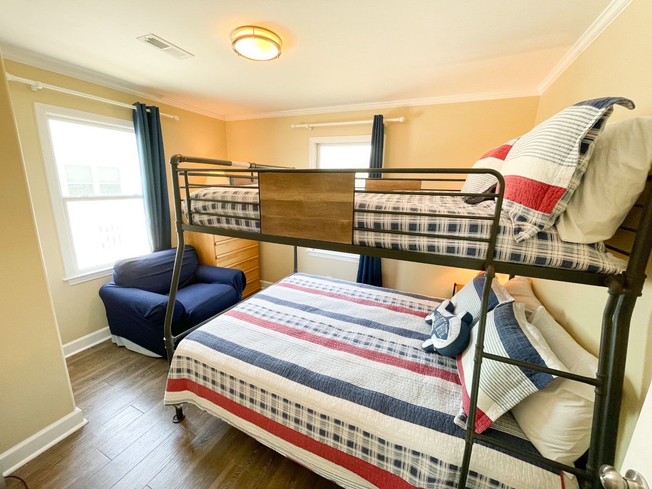Your family will love this cozy bedroom with sturdy bunk beds and patriotic linens, plus a comfy reading chair by sunny windows.