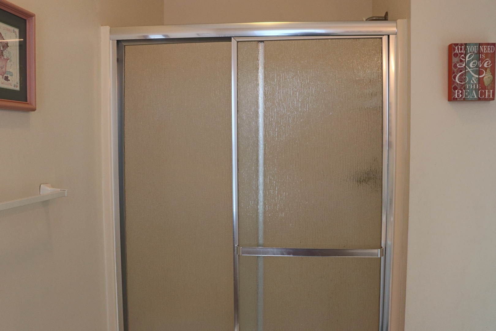 Step into your private shower sanctuary featuring sleek glass doors and cheerful beach-themed décor to brighten your daily routine.