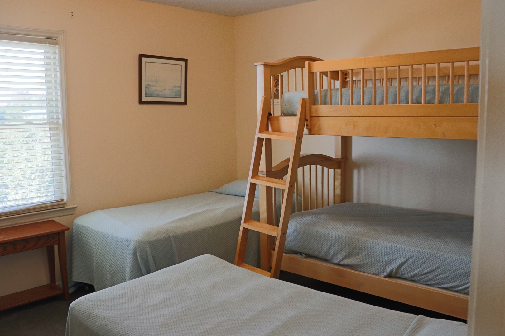 Your family bedroom features sturdy wooden bunk beds and a separate twin bed, perfect for kids' adventures and peaceful sleep.