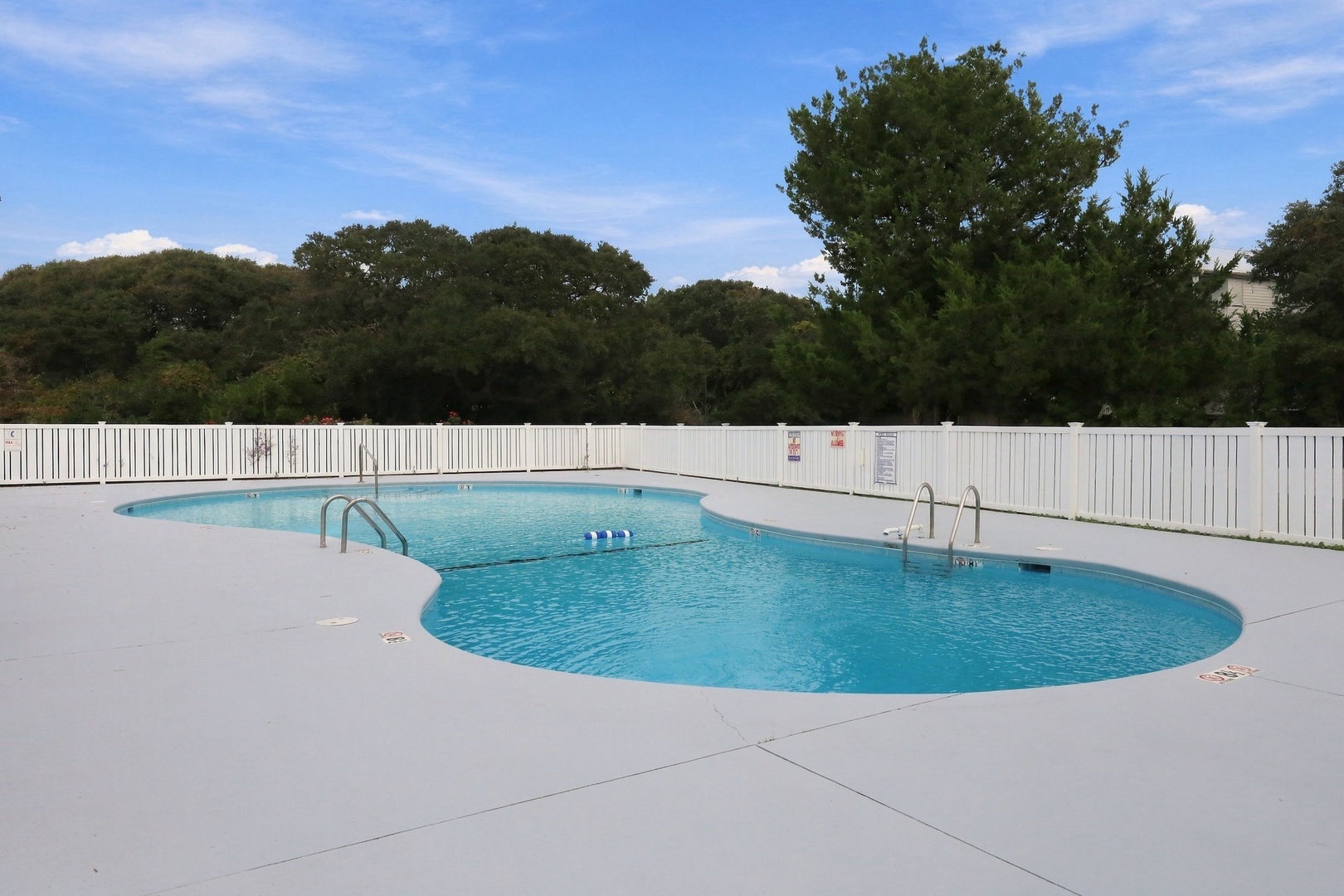 Two sparkling outdoor pools await, framed by lush trees and a bright blue sky—perfect for sunny days spent cooling off and unwinding in a peaceful, private setting.