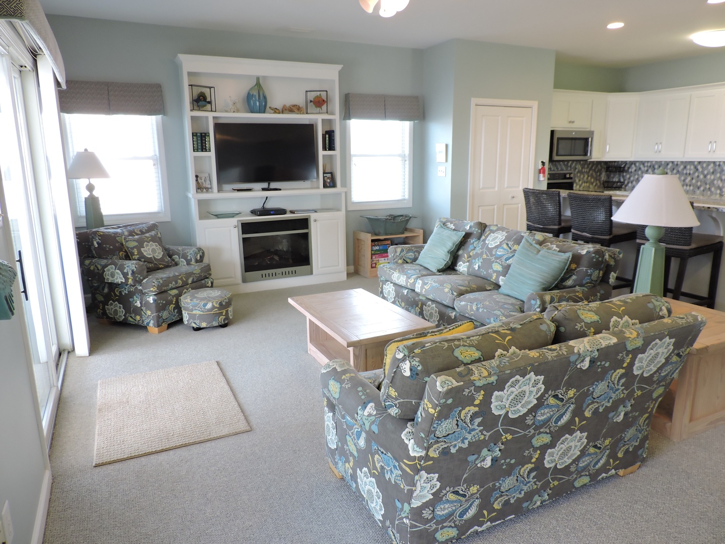 Settle into your bright, coastal living space where soft blue walls and patterned furniture create the perfect retreat for family gatherings.