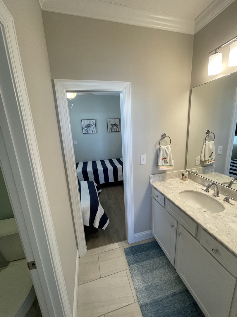 Your beautifully updated bathroom features crisp white vanity, elegant marble countertops, and fresh coastal-inspired decor that makes getting ready a pleasure.