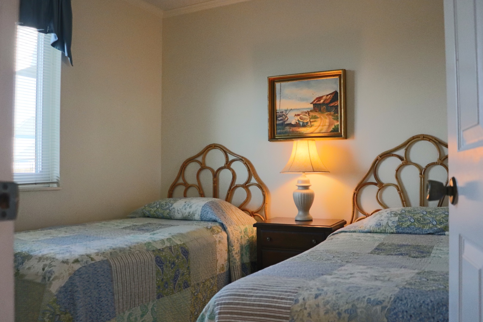 Drift off to sleep in your cozy twin bedroom, where warm lamplight and coastal artwork create the perfect seaside retreat.