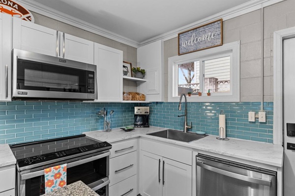 Your bright, fully-equipped kitchen features stainless steel appliances and charming turquoise backsplash, perfect for preparing meals together.