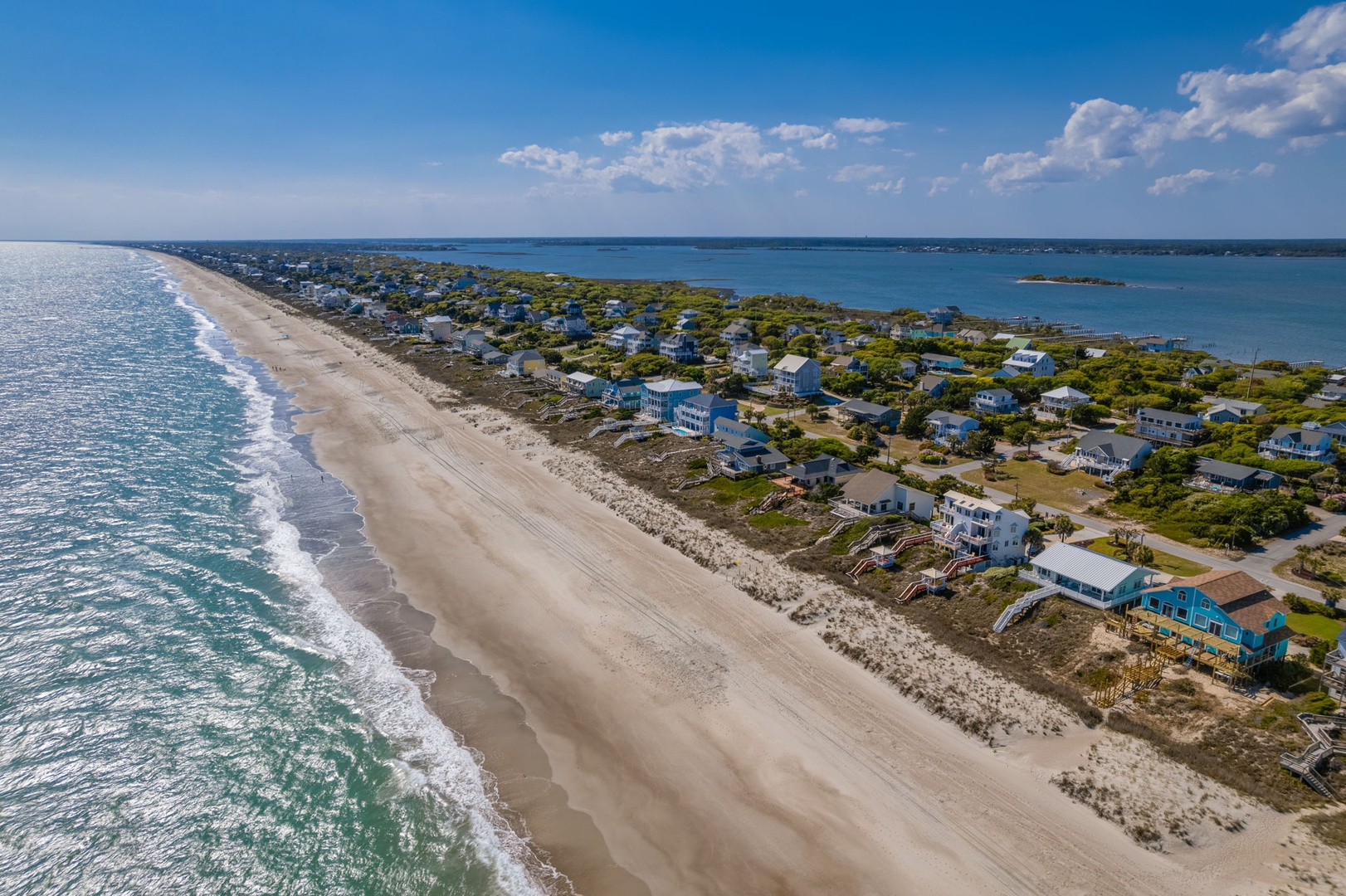 Aerial view showcasing pristine beachfront location with coastal homes nestled between ocean and bay waters.