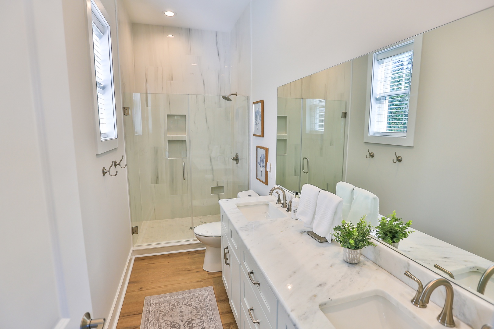 Step into your spa-like bathroom oasis with gleaming marble countertops, rainfall shower, and warm natural light streaming through the windows.