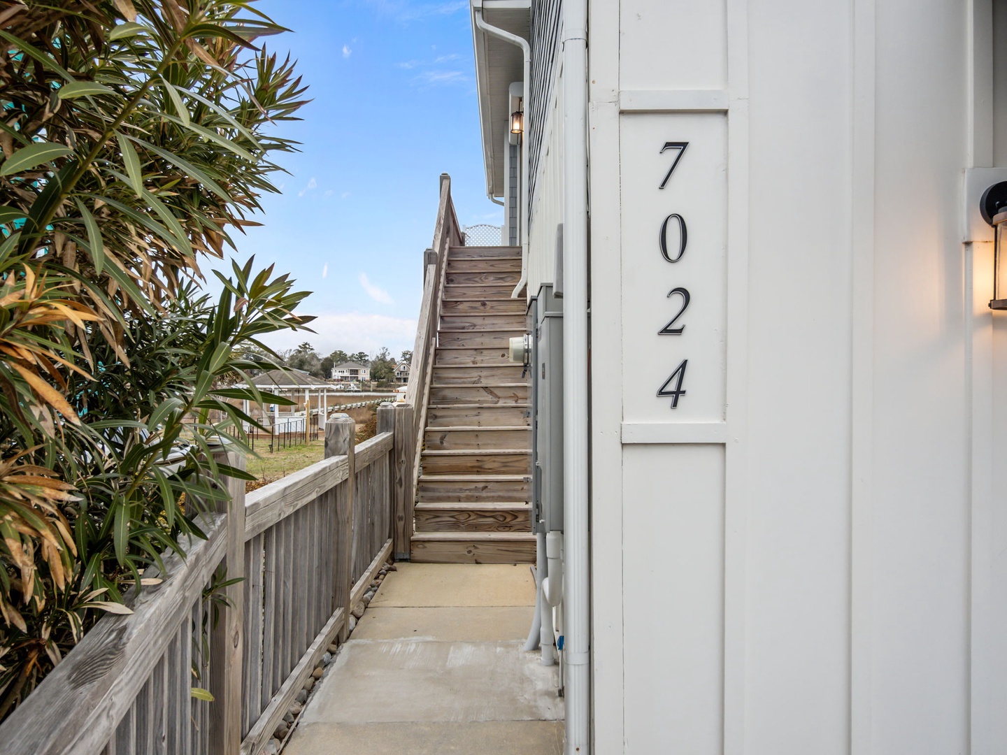 Modern coastal property entrance clearly marked with address number 7024, surrounded by lush tropical landscaping.